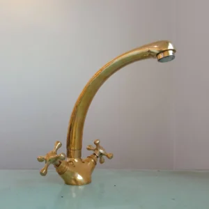 A polished brass kitchen faucet with dual handles and a curved spout, ideal for modern and classic kitchen designs.